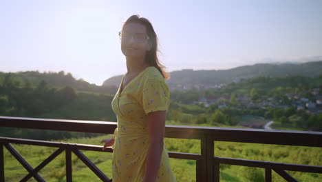 woman in yellow dress on a balcony with beautiful sunset view