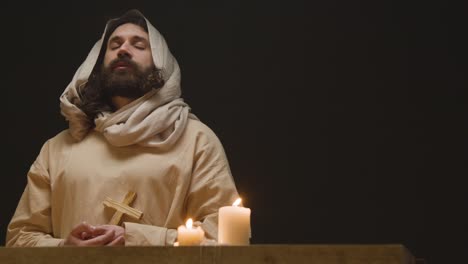 shot of man wearing robes with long hair and beard representing figure of jesus christ holding wooden cross 1