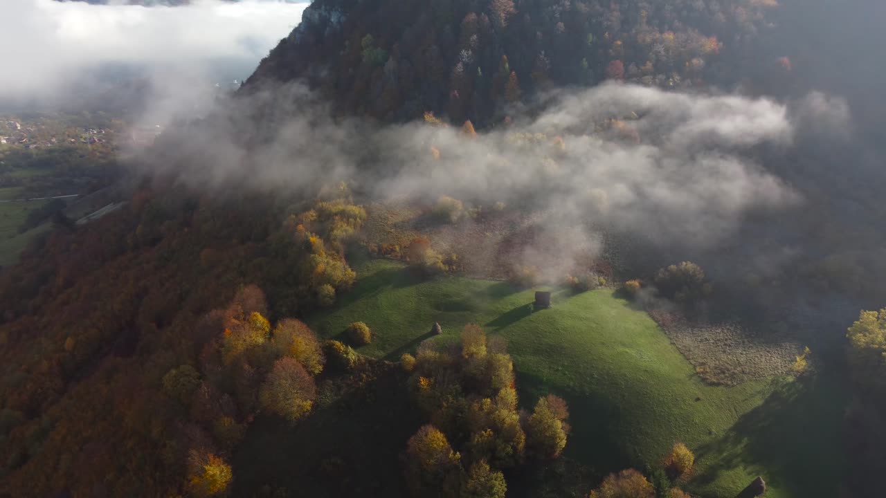 impresionante cabaña remota en las montañas, colores de otoño y vista melancólica al amanecer sobre las nubes en el campo, rumania, toma de órbita