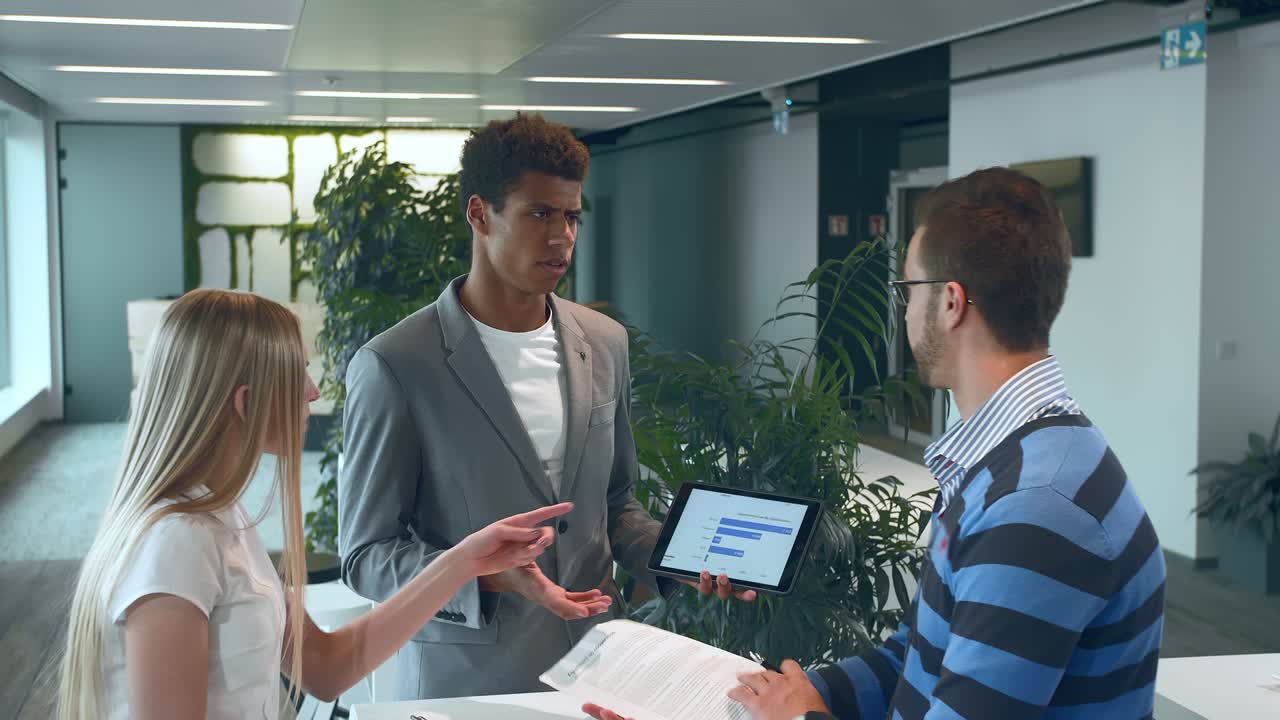 Multiracial men and woman working on report. Group of diverse woman and men with tablet in modern office hall having work with documents and statistics