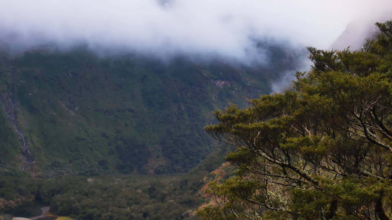 toma amplia de montañas verdes y valle rural con nubes voladoras entre cumbres durante el día ventoso