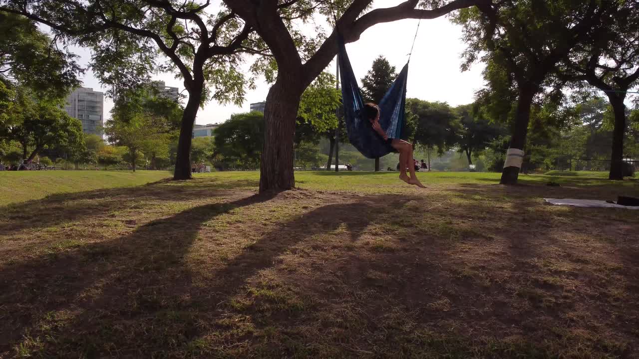 mujer joven descansando en una hamaca en el parque vicente lopez, buenos aires en argentina