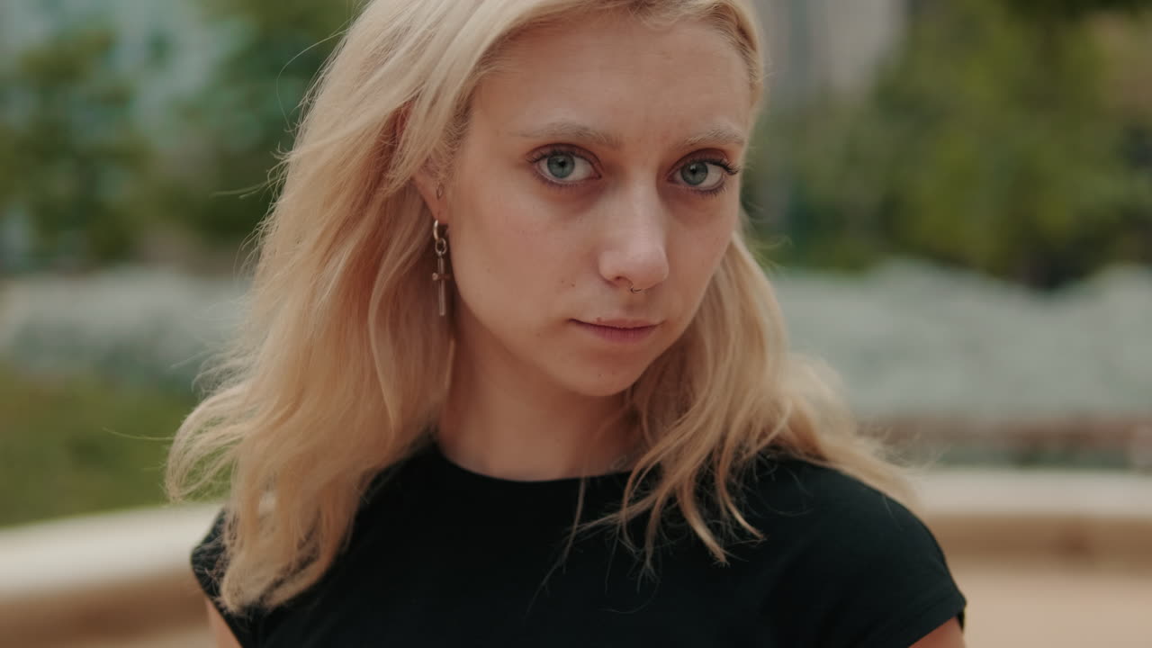 Young Blonde Woman with Serious Expression Looks at Camera