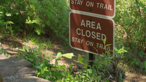 area closed brown sign on nature or national park in usa. trail dangerous to pass. restricted access for hikers or bikers walking or riding on the way in green forest. warning sign for visitors