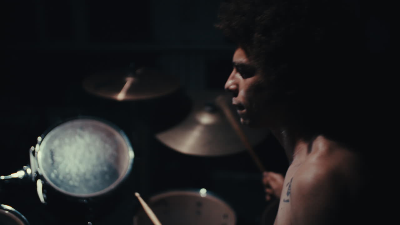 Drummer playing drums in a dark room