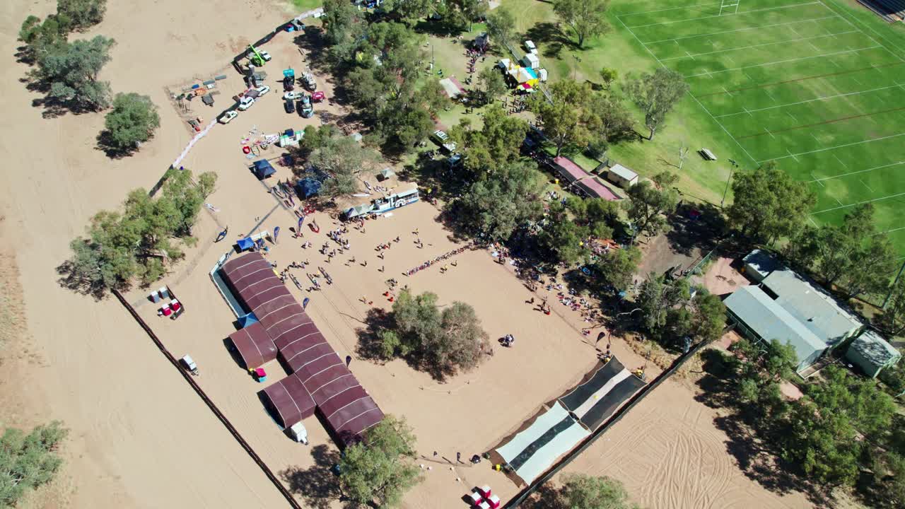 Aerial view of the Henly on Todd Regatta on the dry river bed of the Todd River, and panning up to the town of Alice Springs, Mparntwe. Northern Territory, Australia. August 2022.