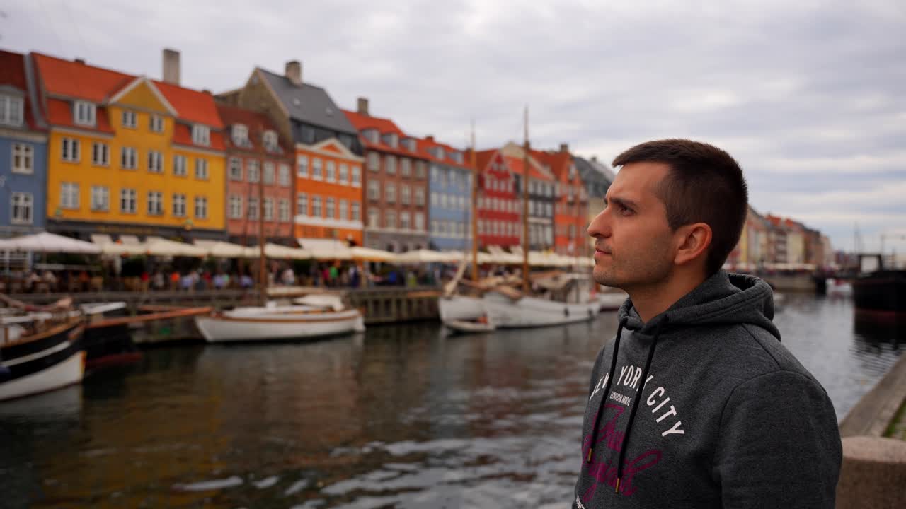 Młody mężczyzna obserwujący atmosferę kultowego miejsca Nyhavn w Kopenhadze
