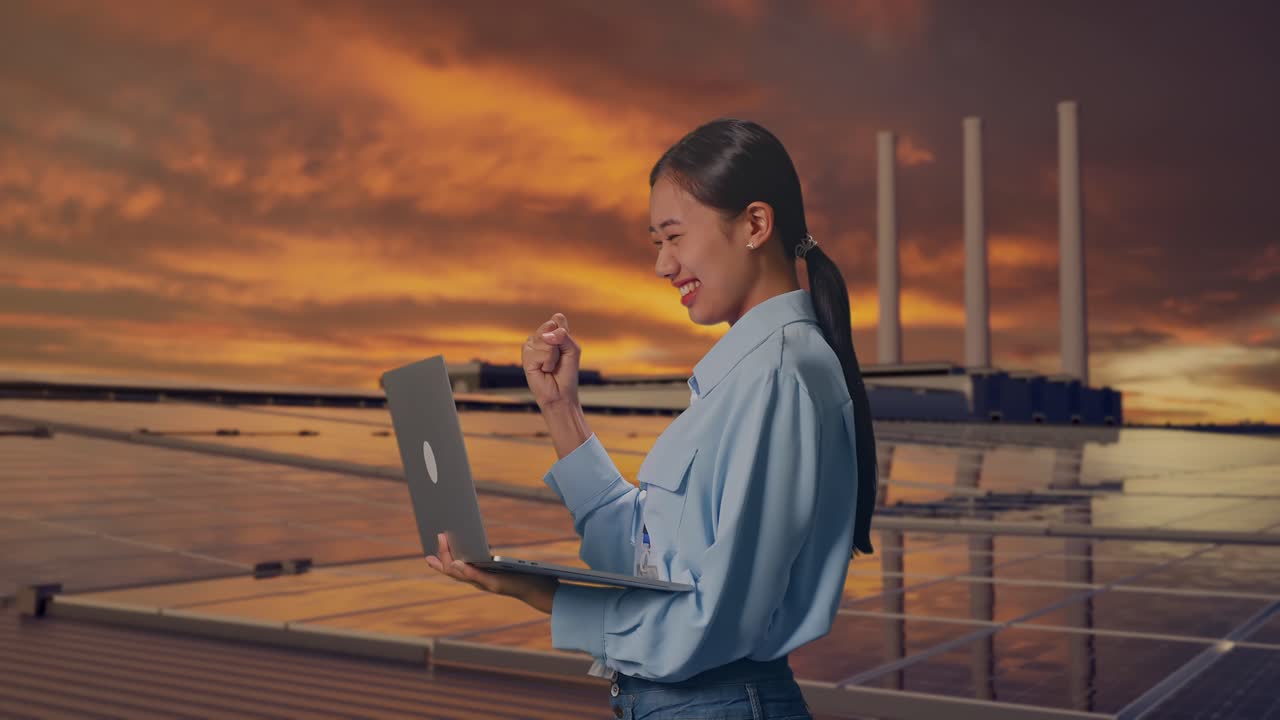 日落時分，一名亞洲女性在屋頂上，手持手提電腦檢查太陽能電池板。她在手提電腦上輸入後，興奮地舉起拳頭高呼成功。