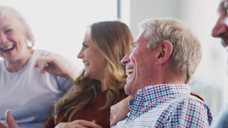 Ältere-Eltern-Mit-Erwachsenen-Nachkommen-Sitzen-Zu-Hause-Auf-Dem-Sofa-Und-Reden-Und-Lachen