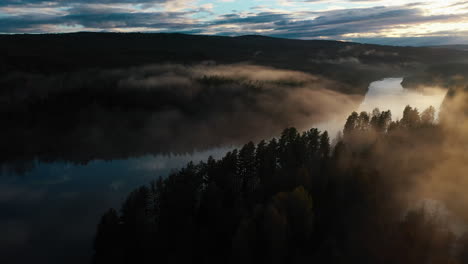 panning aerial shot of a river running through a pine tree forest at dusk