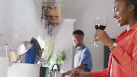 feliz pareja afroamericana preparando comida en la cocina y bebiendo vino