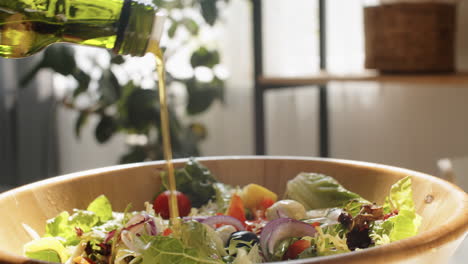 adding olive oil to salad in bowl