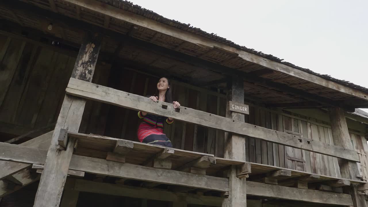 Woman in Traditional Attire at a Wooden House