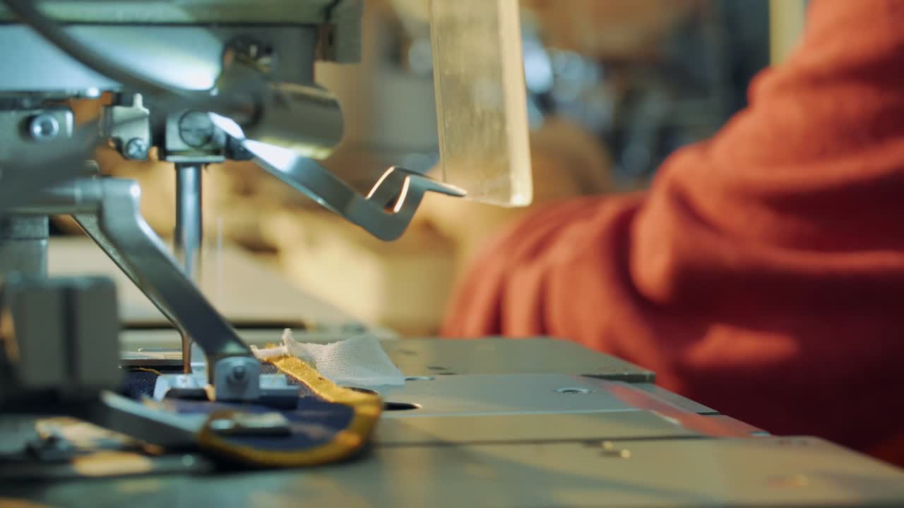 The man working in the clothing factory works on the sewing machine