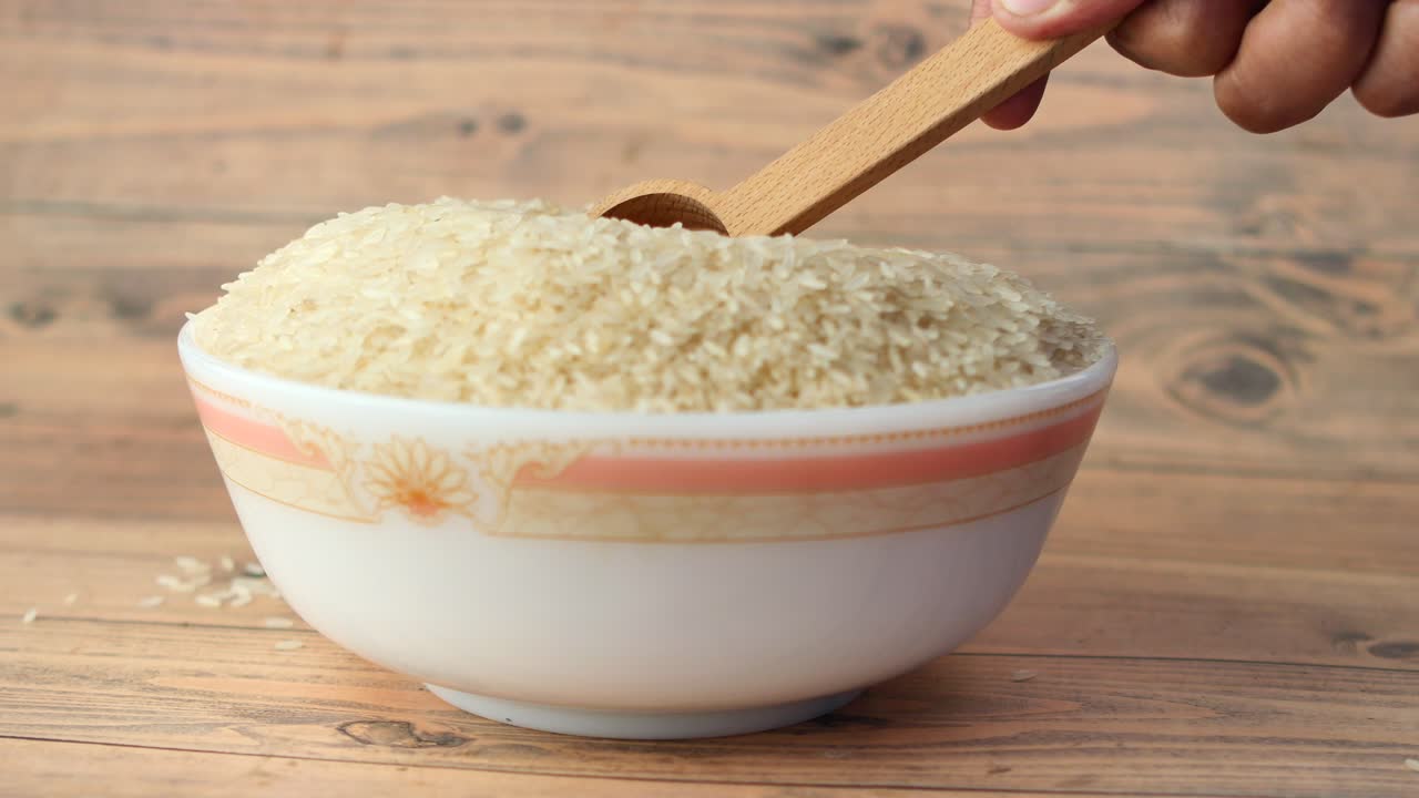 arroz blanco en un cuenco con cuchara de madera