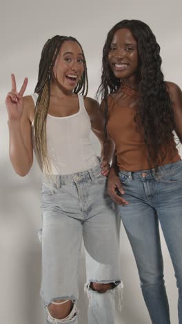 studio beauty portrait shot of two young women laughing and talking as camera rotates