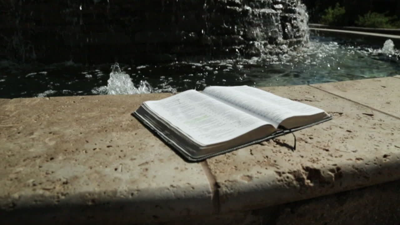 Holy Book by a Peaceful Water Fountain Background in Slow Motion