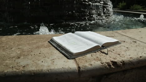 Heiliges-Buch-Vor-Einem-Friedlichen-Wasserfontänen-Hintergrund-In-Zeitlupe