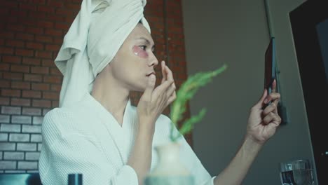woman applying facial mask and eye patches