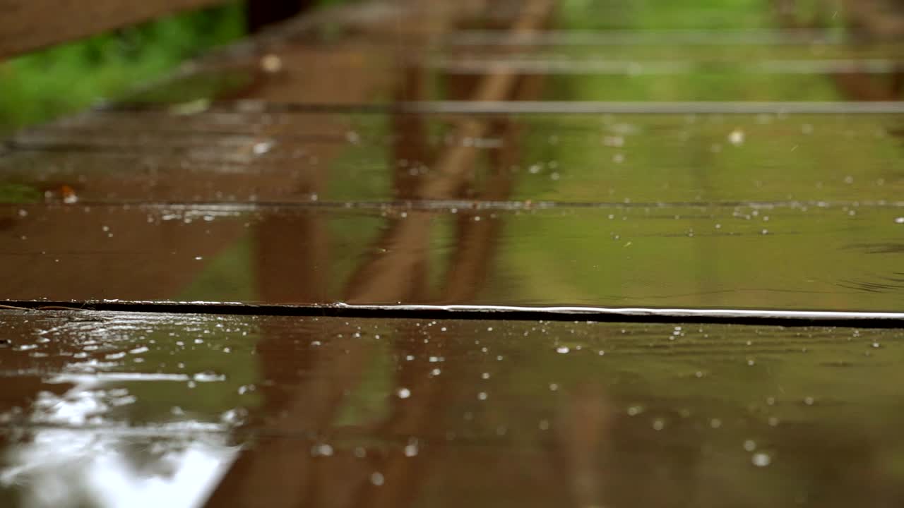 Raindrops hitting the surface of walking bridge in slow motion
