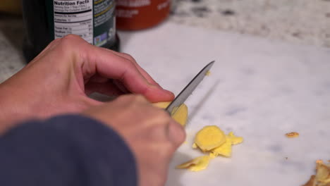 thinly slicing a piece of fresh ginger root