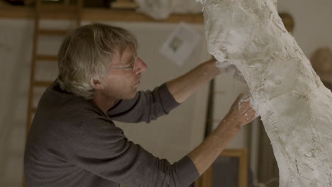 sculptor works on his sculpture with intense focus