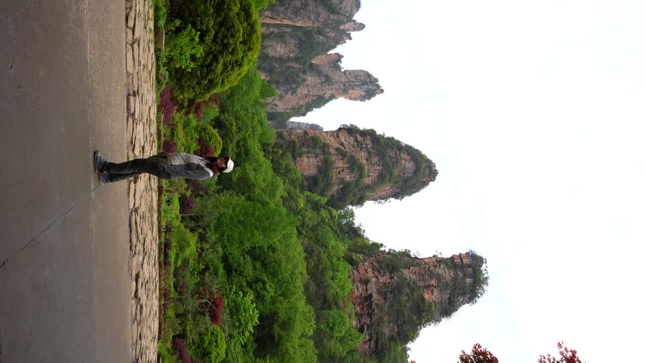 Woman looking to sandstone pillars of Huangshi Village. Vertical