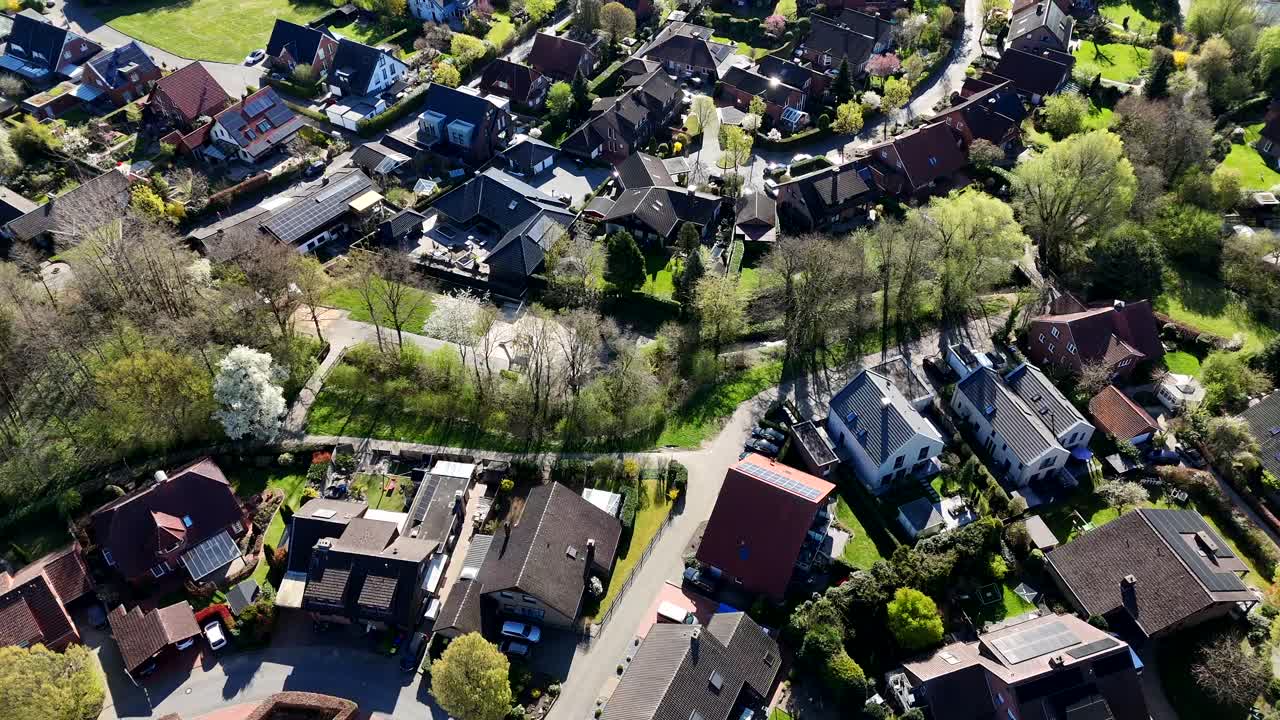 Modern two-story family houses in quiet district of american town.Sunny day with path along tree avenue in spring. Aerial top down flyover. Solar panels in roof of buildings producing cheap energy.