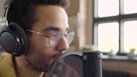 Close-Up-View-Of-Man-Recording-A-Podcast-Wearing-Eyeglasses-And-Headphones-And-Talking-Into-A-Microphone-1