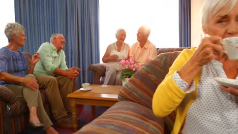 group of happy senior friends interacting while having tea