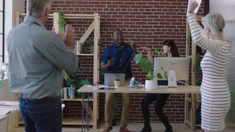 multi-ethnic-business-team-dancing-excited-celebrating-successful-company-start-up-happy-coworkers-cheering-arms-raised-in-modern-office-workspace