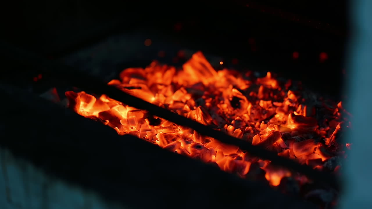 Brennende kull i kjøkkengrill. Nærbilde av kull i restaurantkjøkken.