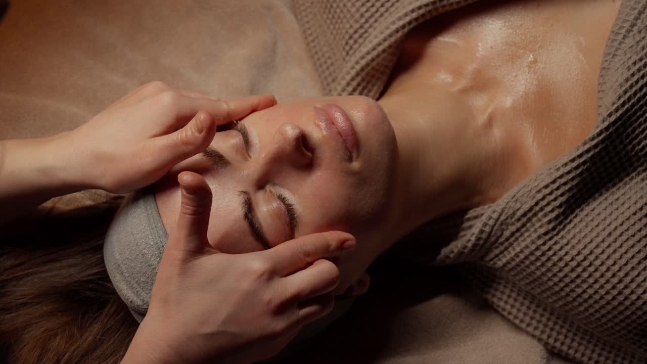 Kvinde får afslappende ansigtsmassage i en spa