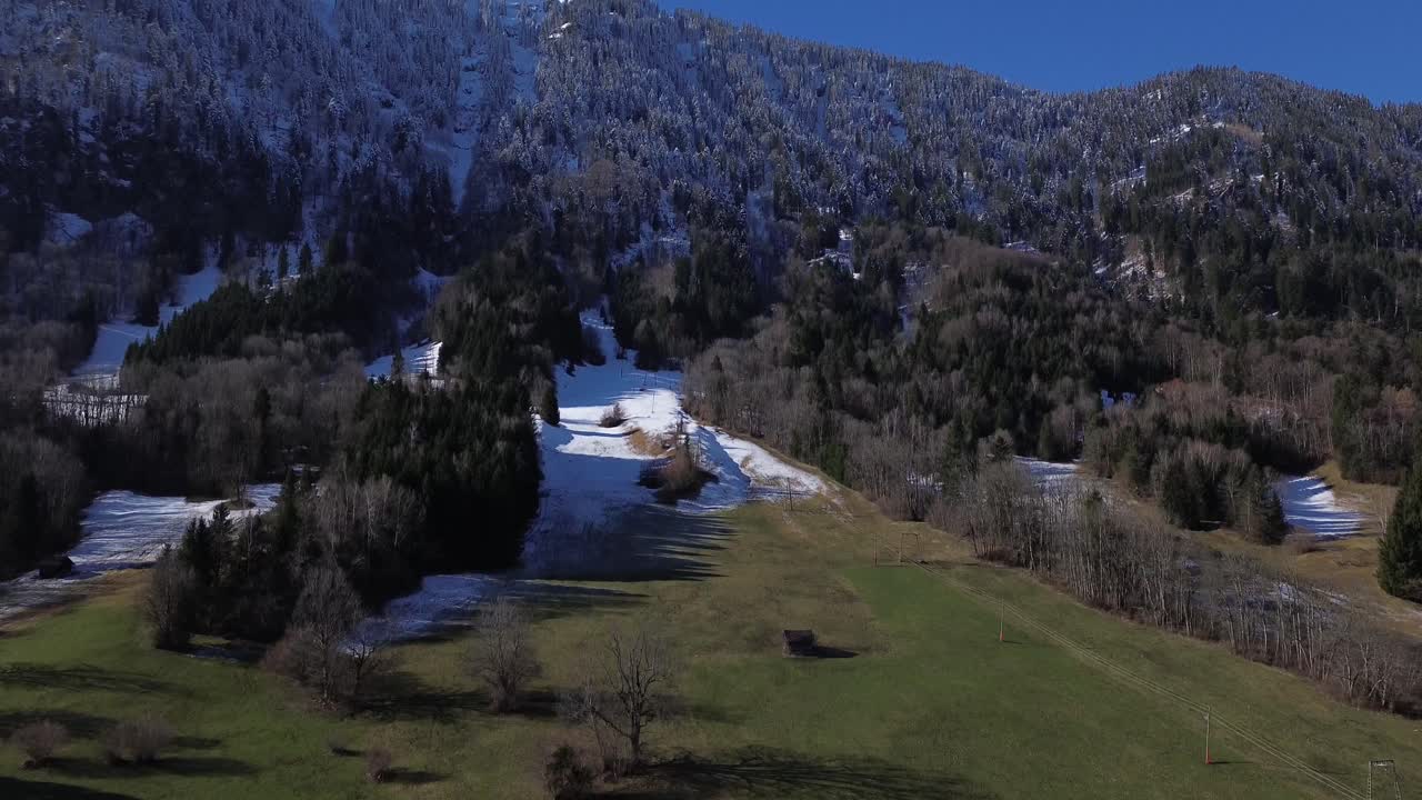 vista aérea de una pista de esquí a finales del invierno en austria, la nieve se derrite lentamente y la hierba verde está volviendo