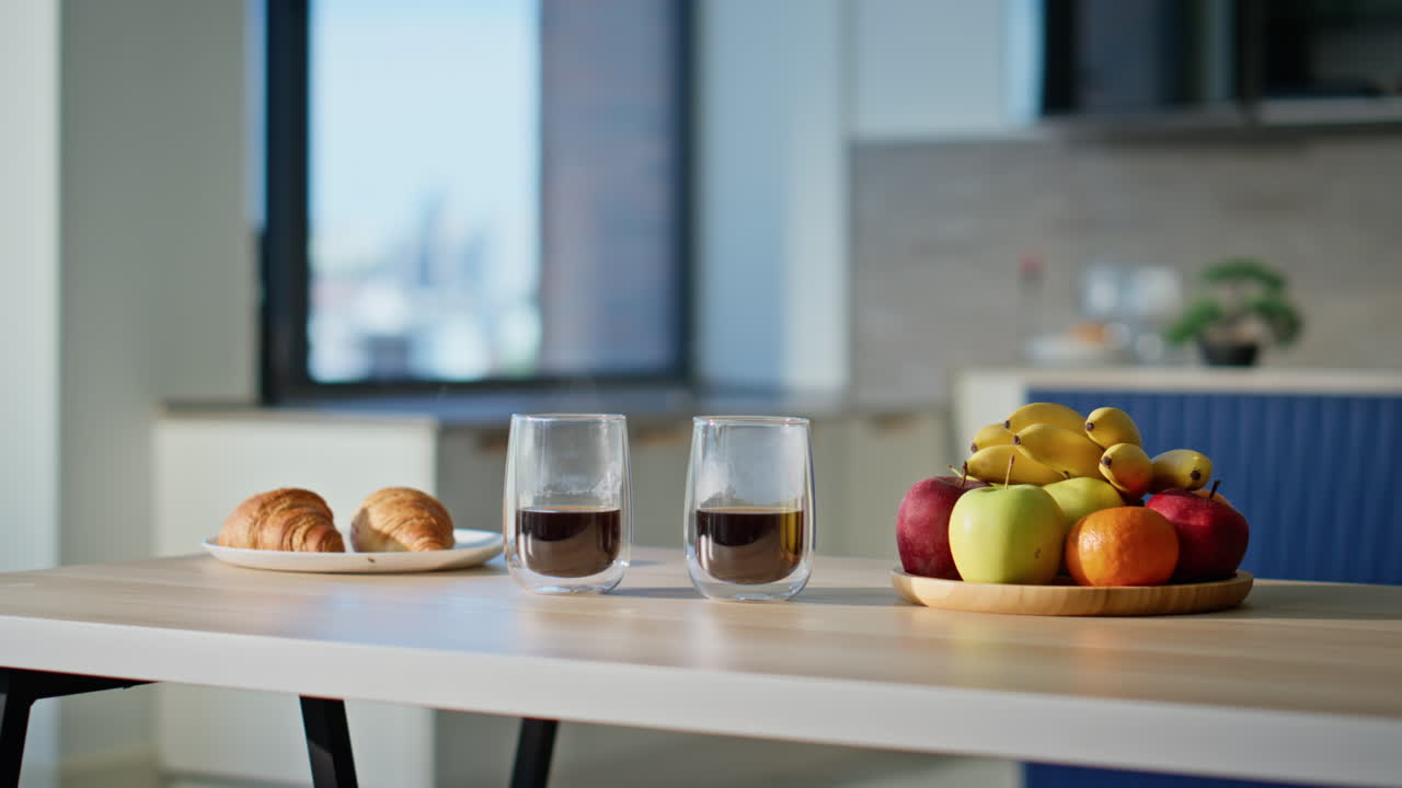 Croissants coffee placed table at modern kitchen closeup. Fresh fruit bowl