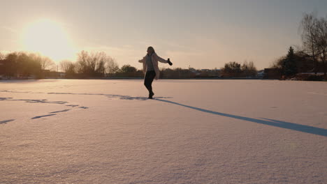 woman enjoying a winter sunset on a frozen lake