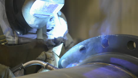 Close-up-footage-of-a-technician-welding-a-large-steel-pipe-in-an-industrial-machine-shop
