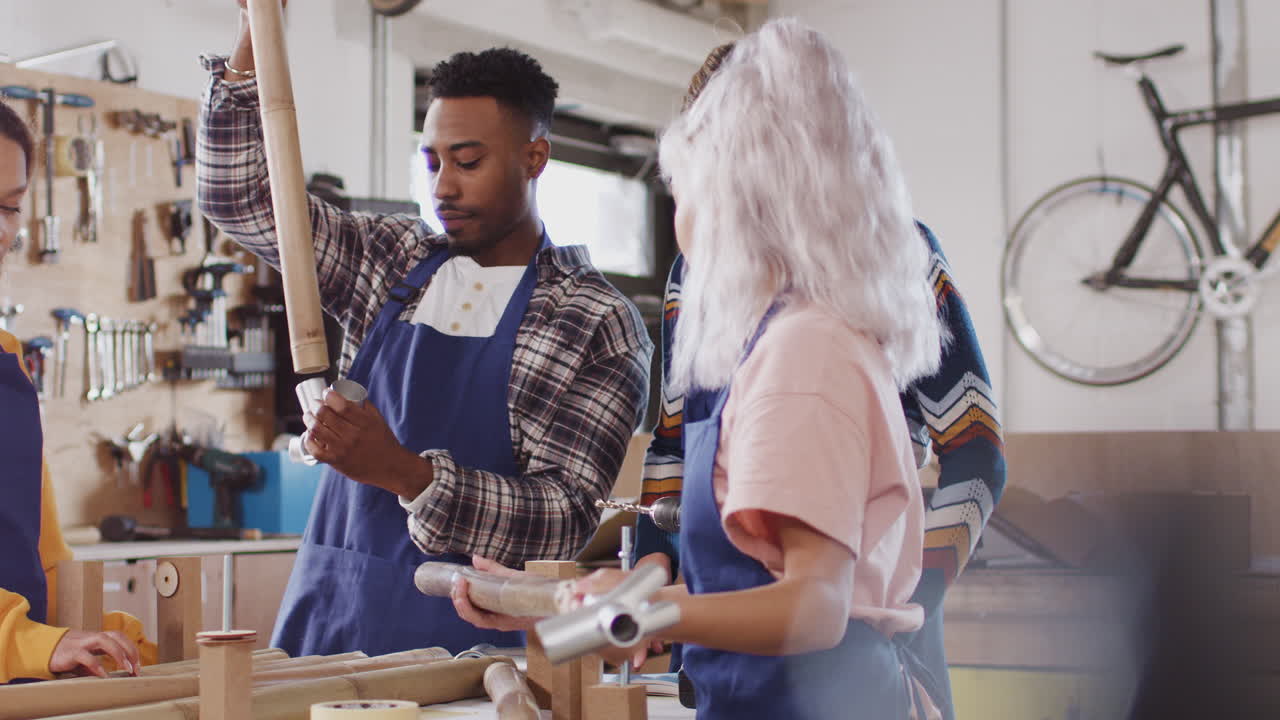 equipo multicultural de aprendices en un taller ensamblando el marco de una bicicleta construida a mano