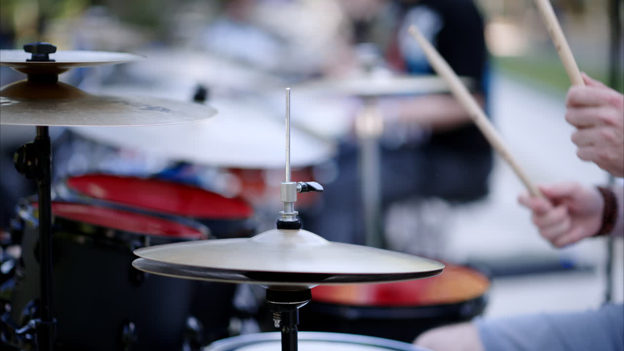 Primo piano di un uomo che suona una batteria rossa all'aperto