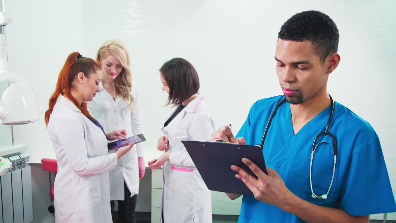 Doctors in the dental office. Three talking nurses and one noting doctor