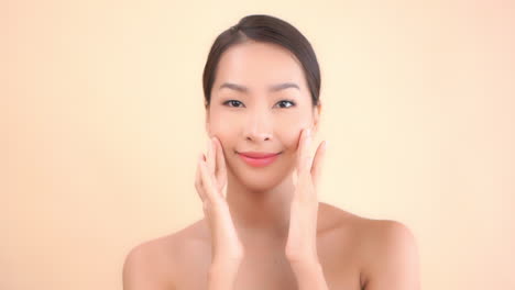 a young beautiful asian woman massages her face gently with her fingertips