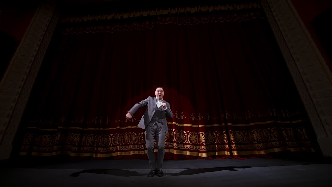 Portrait of a comedian talking. Cheerful actor in suit telling funny stories and gesticulating a lot. Joyful man performing on stage.