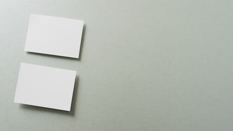 close up of two stacks of white business cards on grey background, copy space, slow motion