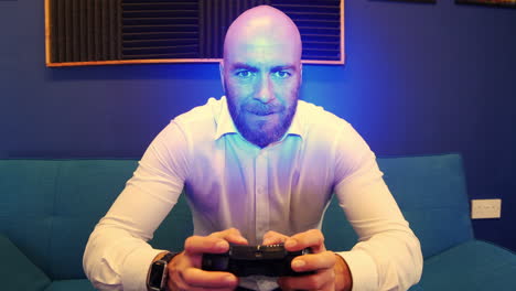 a bearded bald man on couch sofa playing a video game