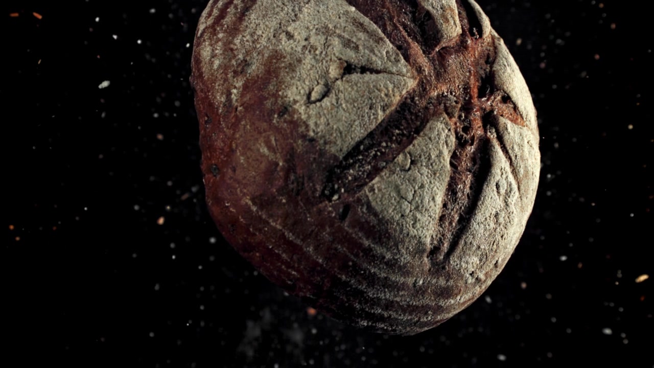 Pagnotta di pane a lievitazione naturale appena sfornata che fluttua con particelle di farina