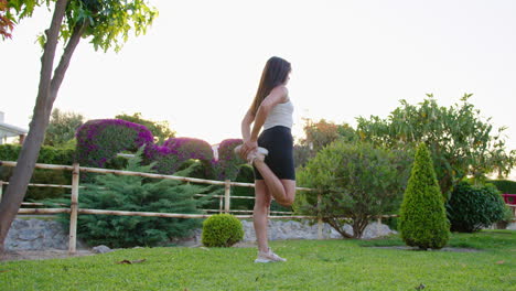 Wide-shot-of-a-young-woman-stretching-in-the-park-after-exercise,-wellness-and-fitness-lifestyle