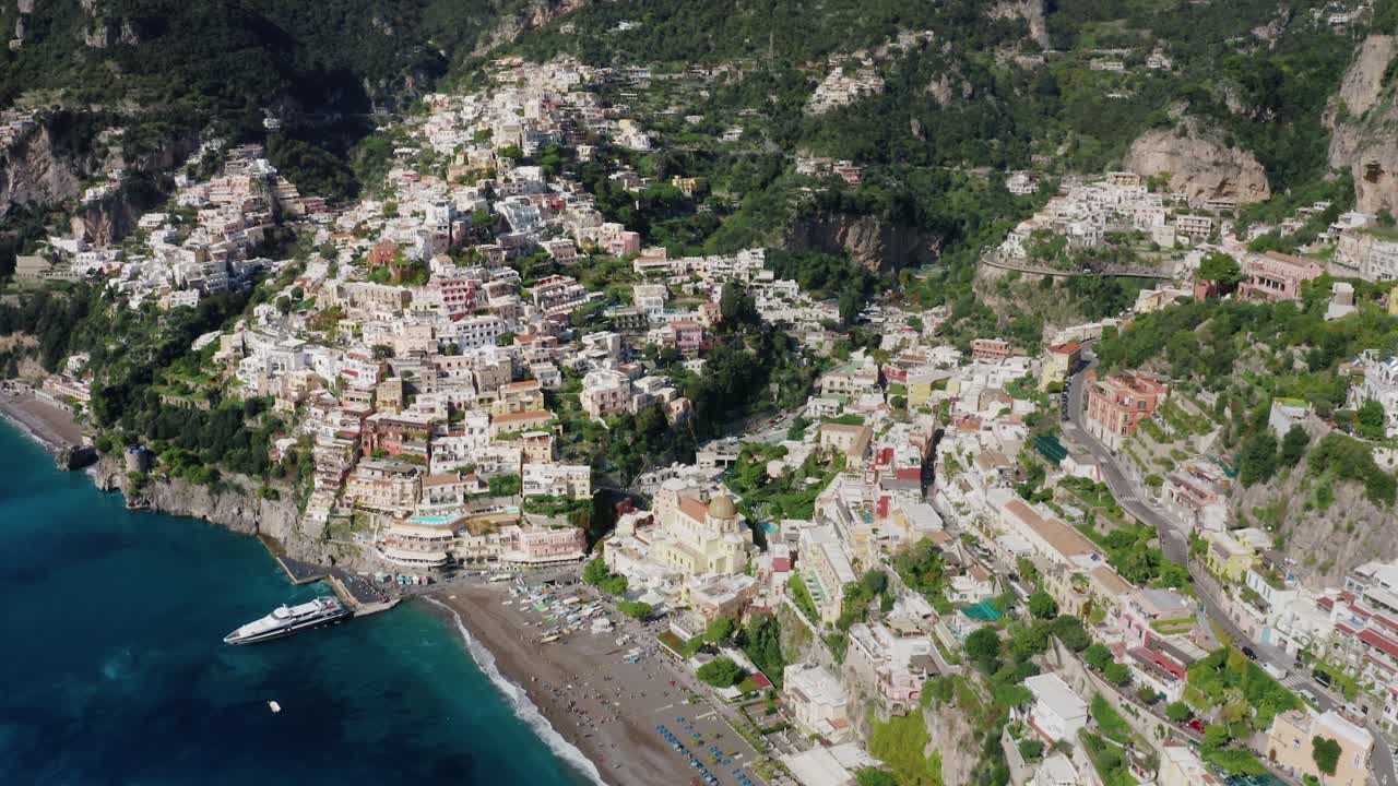 Veduta aerea dall'alto del famoso villaggio di Positano in Costiera Amalfitana. La destinazione turistica più popolare d'Italia con case colorate aggrappate alla scogliera che si affacciano sulla spiaggia con una barca ormeggiata.