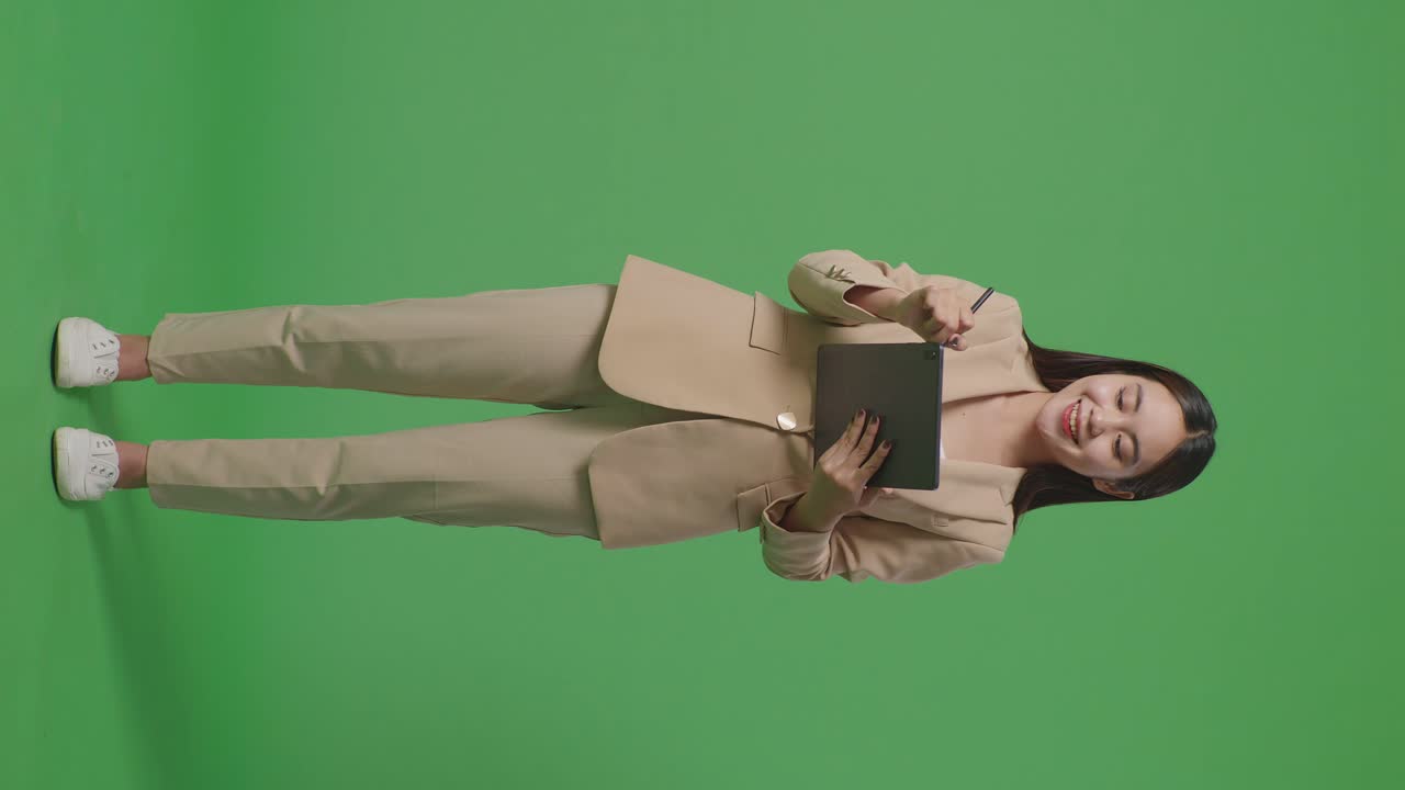 cuerpo lleno de mujer de negocios asiática escribiendo tableta en el fondo de la pantalla verde en el estudio