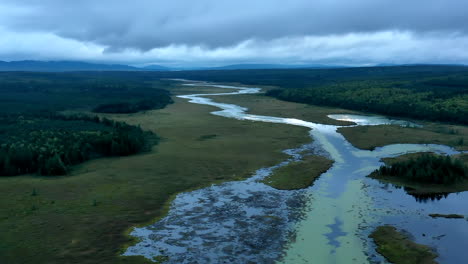 Aerial-hyperlapse-flying-over-a-dark-ominous-landscape-with-the-still-waters-of-Shirley-Bog-winding-through-the-forested-Maine-countryside-and-reflections-of-the-stormy-sky-above