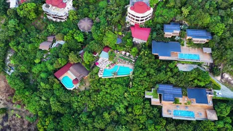 Luxury-resort-on-hillside-covered-in-jungle-in-Thailand,-aerial-view